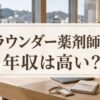 「ラウンダー薬剤師の年収は高い？」と書かれたアイキャッチ画像。窓際の木のテーブルにノートパソコンと手帳が置かれている。